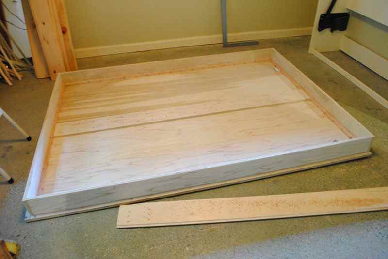 Assembling the wooden bed frame with screws and clamps.