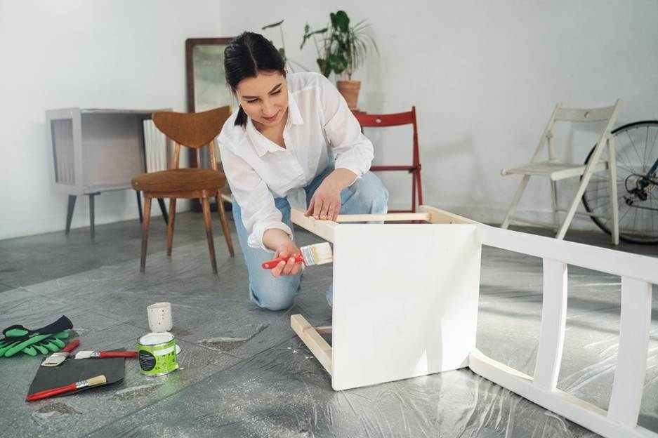 a woman painting a chair.